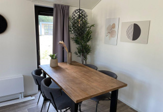 Spisestue i Forest Lodge ved De Zanding i Holland, moderne træbord, grå stole og kunstværker på væggen.
