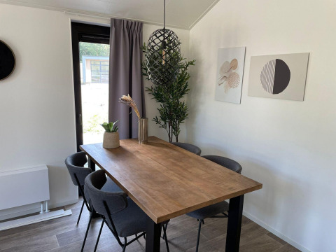 Salle à manger à Forest Lodge à De Zanding, Pays-Bas, table en bois, chaises grises et tableaux muraux.