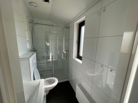 Baño moderno en el Forest Lodge, De Zanding, Países Bajos, con ducha, inodoro y ventana amplia.