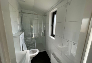 Baño moderno en el Forest Lodge, De Zanding, Países Bajos, con ducha, inodoro y ventana amplia.