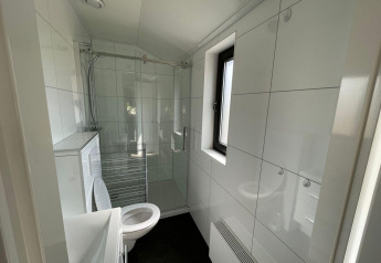 Baño moderno en el Forest Lodge, De Zanding, Países Bajos, con ducha, inodoro y ventana amplia.