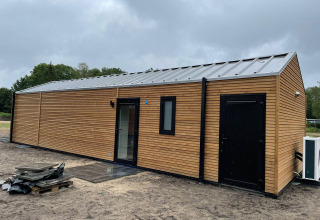 Et foto af Forest Lodge ved De Zanding i Nederlandene, der viser en moderne træhytte på en overskyet dag.