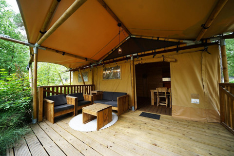Salon extérieur d’une tente safari Lodgetent à De Zanding, Pays-Bas, avec mobilier en bois.