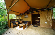 Salon extérieur d’une tente safari Lodgetent à De Zanding, Pays-Bas, avec mobilier en bois.