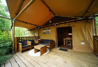 Salon extérieur d’une tente safari Lodgetent à De Zanding, Pays-Bas, avec mobilier en bois.