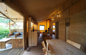 Interior de una tienda safari Lodgetent en De Zanding, Países Bajos, con muebles de madera y ambiente acogedor.