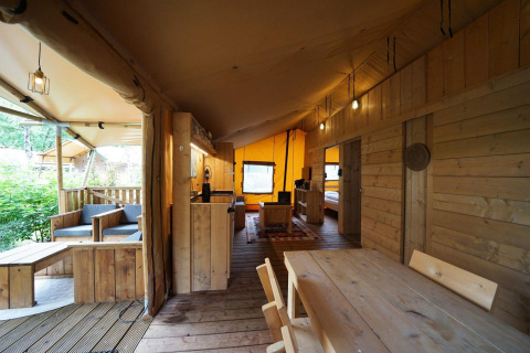 Intérieur d'une tente safari Lodgetent à De Zanding, Pays-Bas, avec mobilier en bois et ambiance chaleureuse.