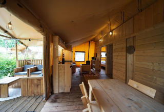Interior de una tienda safari Lodgetent en De Zanding, Países Bajos, con muebles de madera y ambiente acogedor.