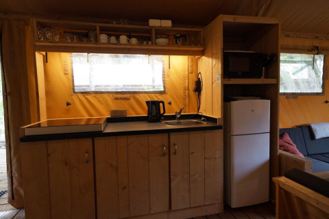 Küchenbereich im Safarizelt Lodgetent bei De Zanding, Niederlande, mit Kühlschrank und Geschirr.