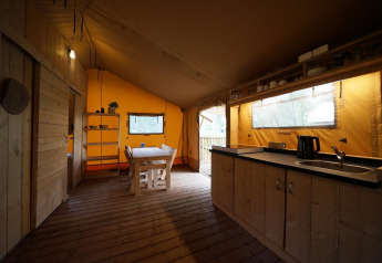 Indvendig udsigt af en safaritelts lodge ved De Zanding i Holland, med træmøbler og køkken.