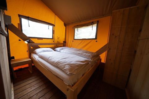 Cozy bedroom with double bed inside a safari lodgetent at De Zanding campsite in the Netherlands.
