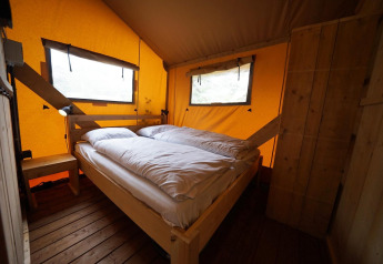 Cozy bedroom with double bed inside a safari lodgetent at De Zanding campsite in the Netherlands.