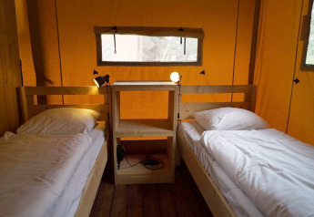 Interno della tenda safari Lodgetent a De Zanding, Paesi Bassi, con due letti singoli e scaffale in legno.