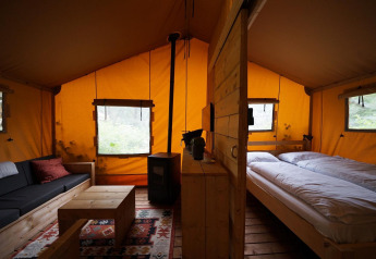 Innenansicht eines Safarizelts Lodgetent bei De Zanding, Niederlande, mit Bett, Sofa und Holztisch.