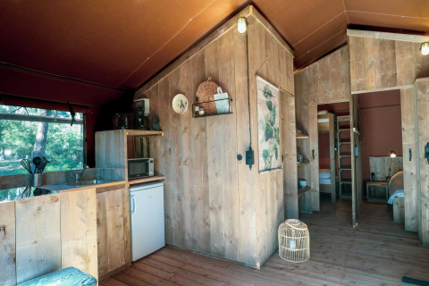 Intérieur d'une tente safari Lodgetent à De Zanding, Pays-Bas, avec cuisine en bois et décoration chaleureuse.
