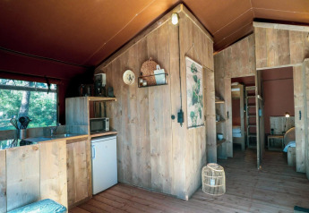 Intérieur d'une tente safari Lodgetent à De Zanding, Pays-Bas, avec cuisine en bois et décoration chaleureuse.