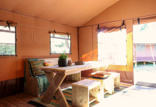 Intérieur d'une tente safari avec table et banc en bois à Lodgetent De Zanding, Pays-Bas.