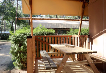 Buitenterras met houten tafel en banken bij Lodgetent safaritent op De Zanding in Nederland.