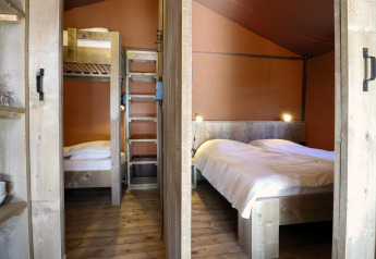 Interieur van safaritent Lodgetent op De Zanding in Nederland, met stapelbed en tweepersoonsbed van hout.