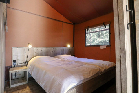 Chambre avec lit double et décor en bois dans une tente safari Lodgetent à De Zanding, Pays-Bas.