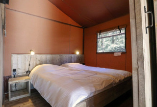 Chambre avec lit double et décor en bois dans une tente safari Lodgetent à De Zanding, Pays-Bas.