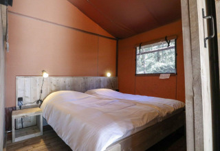 Dormitorio acogedor con cama doble y muebles de madera en la Lodgetent de De Zanding, Países Bajos.