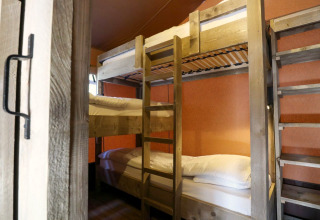 Vue intérieure de lits superposés dans une tente safari Lodgetent à De Zanding, Pays-Bas, avec meubles en bois.