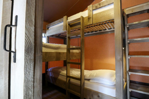 Vue intérieure de lits superposés dans une tente safari Lodgetent à De Zanding, Pays-Bas, avec meubles en bois.
