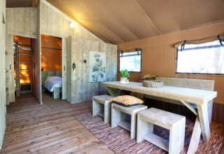 Interior de la tienda safari Lodgetent en De Zanding, Países Bajos, con muebles y decoración de madera.