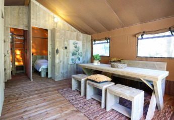 Interior de la tienda safari Lodgetent en De Zanding, Países Bajos, con muebles y decoración de madera.