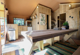 Interior de la tienda safari Lodgetent en De Zanding, Países Bajos, con muebles rústicos de madera.