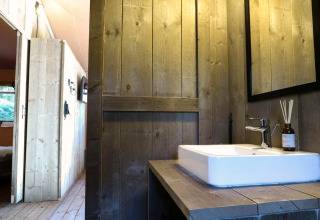 Salle de bain avec murs en bois et lavabo dans une tente safari Lodgetent à De Zanding, Pays-Bas.