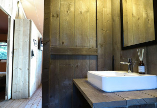 Badezimmer mit Holzverkleidung und Waschbecken in einem Safari-Lodgetent bei De Zanding, Niederlande.