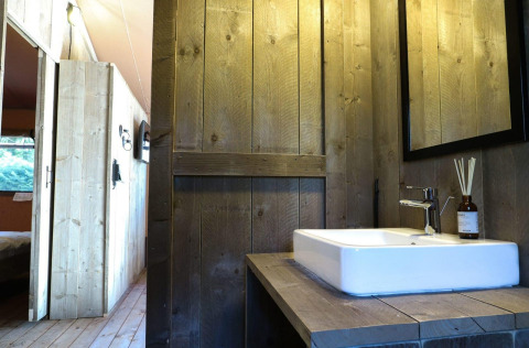Baño con paredes de madera y lavabo en una tienda safari Lodgetent en De Zanding, Países Bajos.