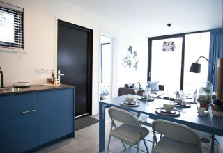 Lodge moderne Modus L à De Zanding aux Pays-Bas avec cuisine bleue, salle à manger et salon lumineux.