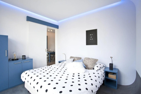 Dormitorio moderno en Modus L de De Zanding, Países Bajos, con muebles azules y luz ambiente.