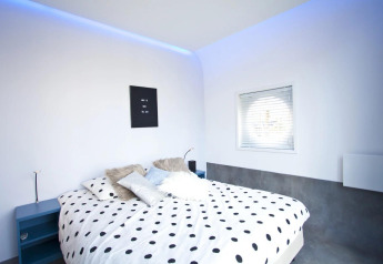 Chambre moderne au Modus L, De Zanding, Pays-Bas avec linge à pois et éclairage d'ambiance bleu.