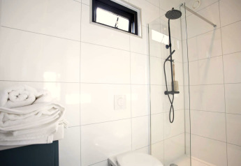 Modernes Badezimmer im Modus L, De Zanding, Niederlande, mit Regendusche, Glaswand und frischen Handtüchern.