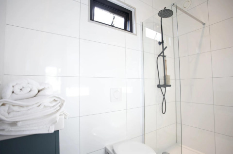 Baño moderno en Modus L, De Zanding, Países Bajos, con ducha de lluvia, panel de vidrio y toallas limpias.