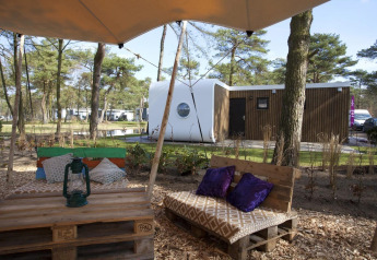 Buitenzithoek met houten palettenbank en olielamp bij Modus L lodge op De Zanding, Nederland, in het bos.