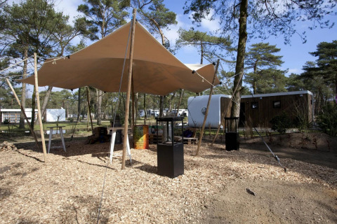 Outdoor area with tent canopy and modern lodges at Modus L, De Zanding, Netherlands.