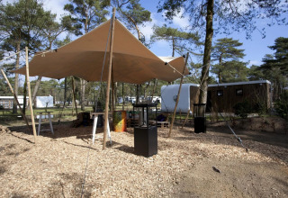 Outdoorbereich mit Sonnensegel und modernen Lodges im Modus L, De Zanding, Niederlande.