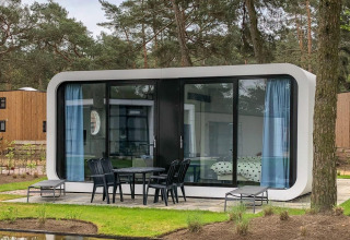 Modern Modus L lodge at De Zanding in the Netherlands, featuring glass façade, patio seating, and pine trees.