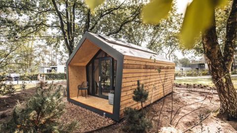 Modernes Solo Retreat aus Holz mit großen Fenstern inmitten eines bewaldeten, ruhigen Naturgebiets.