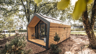 Modernes Solo Retreat aus Holz mit großen Fenstern inmitten eines bewaldeten, ruhigen Naturgebiets.