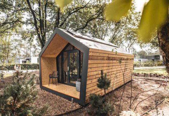 Modernes Solo Retreat aus Holz mit großen Fenstern inmitten eines bewaldeten, ruhigen Naturgebiets.