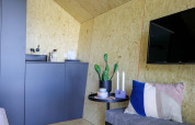 Modernes Lodge-Interieur mit kleiner Küche, Topfpflanze und Fernseher im Solo Retreat De Zanding.