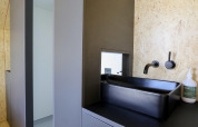 Baño moderno con lavabo cuadrado negro, grifo de pared y dispensador de jabón en De Zanding, Países Bajos.