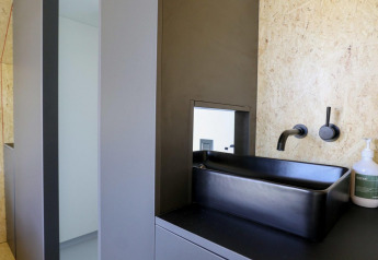 Baño moderno con lavabo cuadrado negro, grifo de pared y dispensador de jabón en De Zanding, Países Bajos.