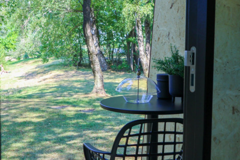 Mesa y silla en Solo retreat en De Zanding, Países Bajos, con vista al jardín verde y los árboles afuera.